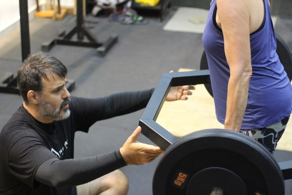 Personal trainer em Copacabana corrigindo postura de aluno em treino personalizado